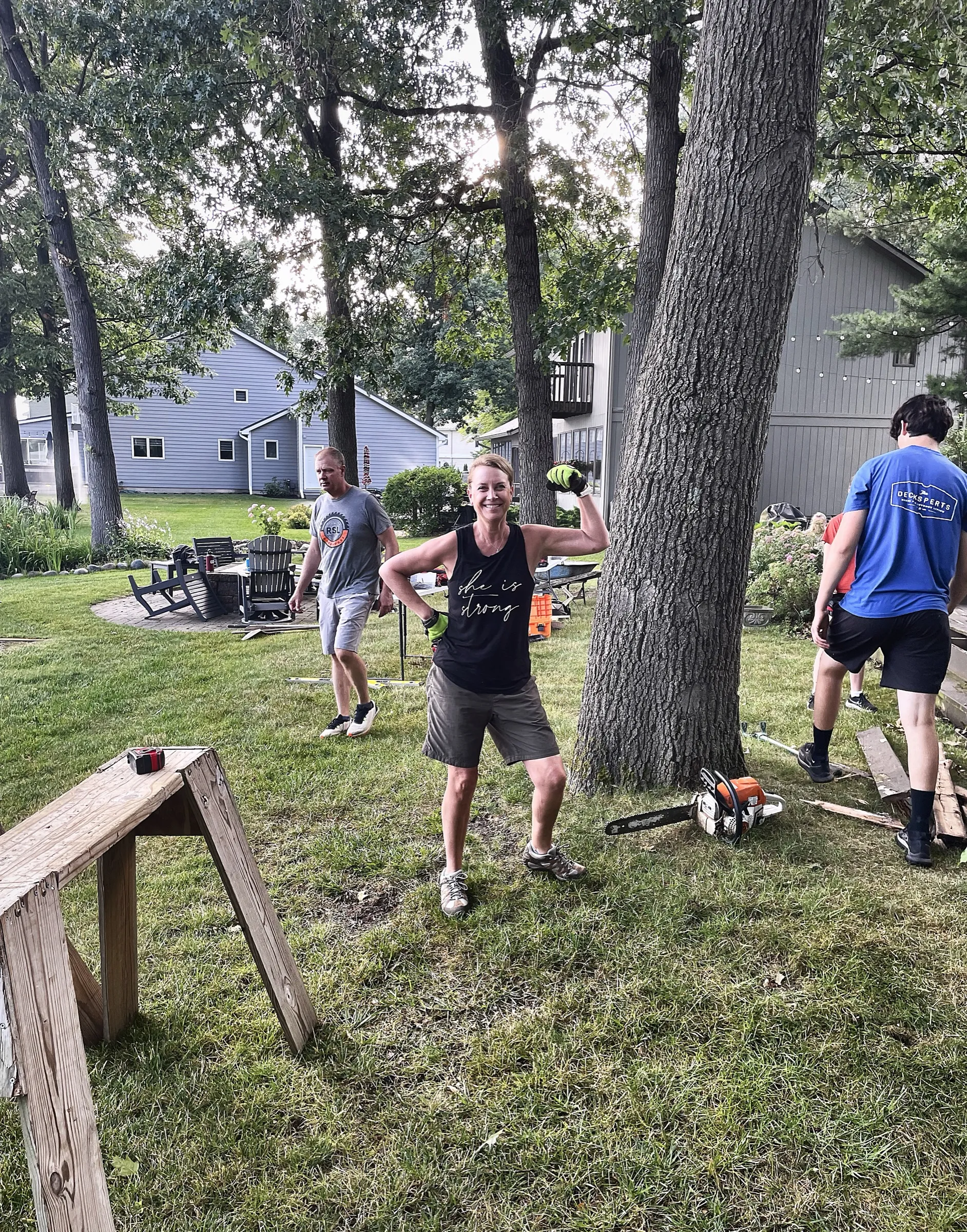 A crew member flexing playfully at the jobsite while the team works in the background